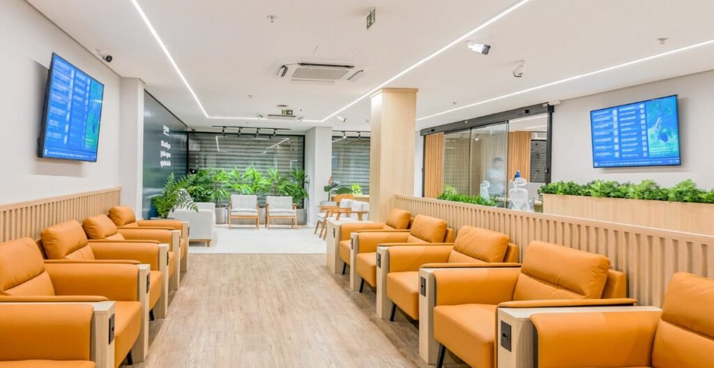Sala de espera da BR MED com poltronas laranja, jardim interno e painéis de senha