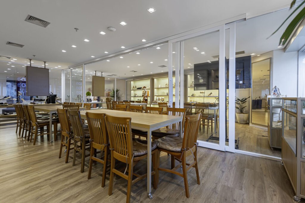 Showroom da MR.CAT com mesa longa e cadeiras de madeira junto às janelas