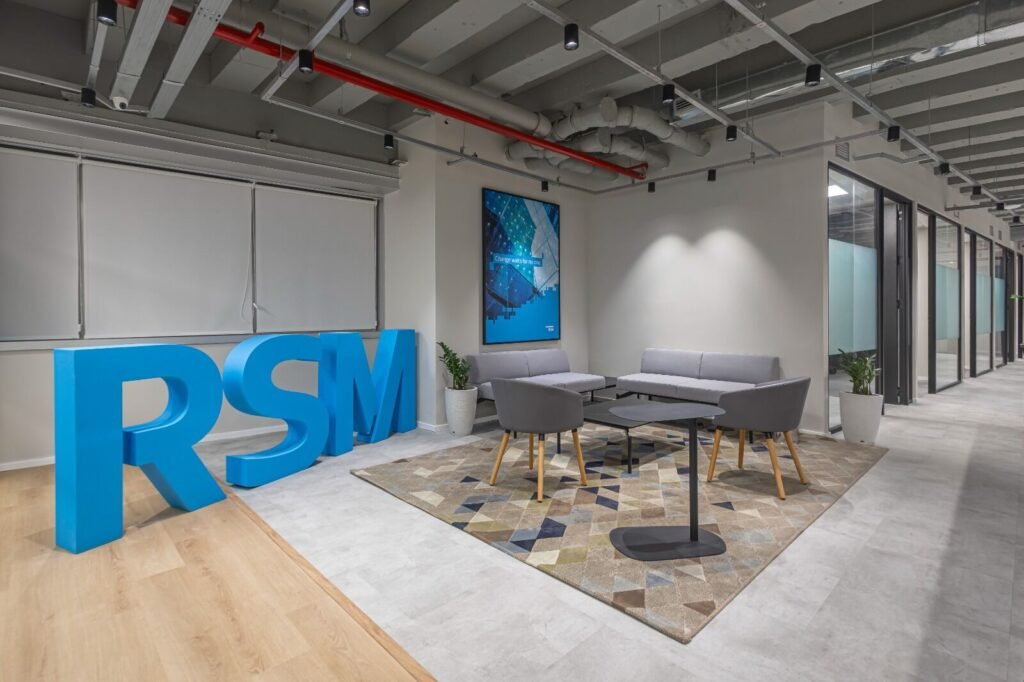 Lounge da RSM com letreiro da marca, tapete e poltronas de espera