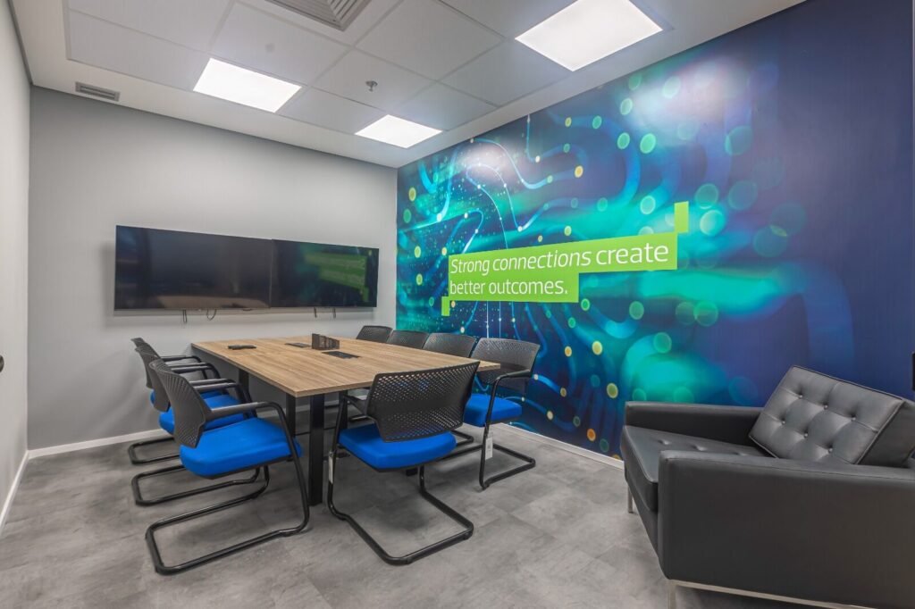 Sala de reunião da RSM com mural verde iluminado e cadeiras azuis