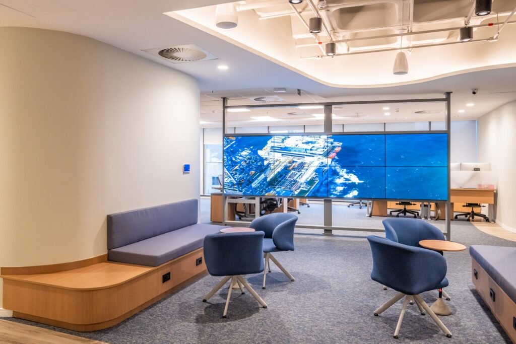 Lounge com videowall e bancos de madeira na Transocean